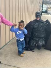 A child meeting a Batman-costumed visitor during community outreach